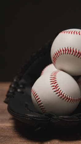 Vertical-Video-Close-Up-Studio-Baseball-Still-Life-With-Balls-And-Catchers-Mitt-On-Wooden-Floor-5